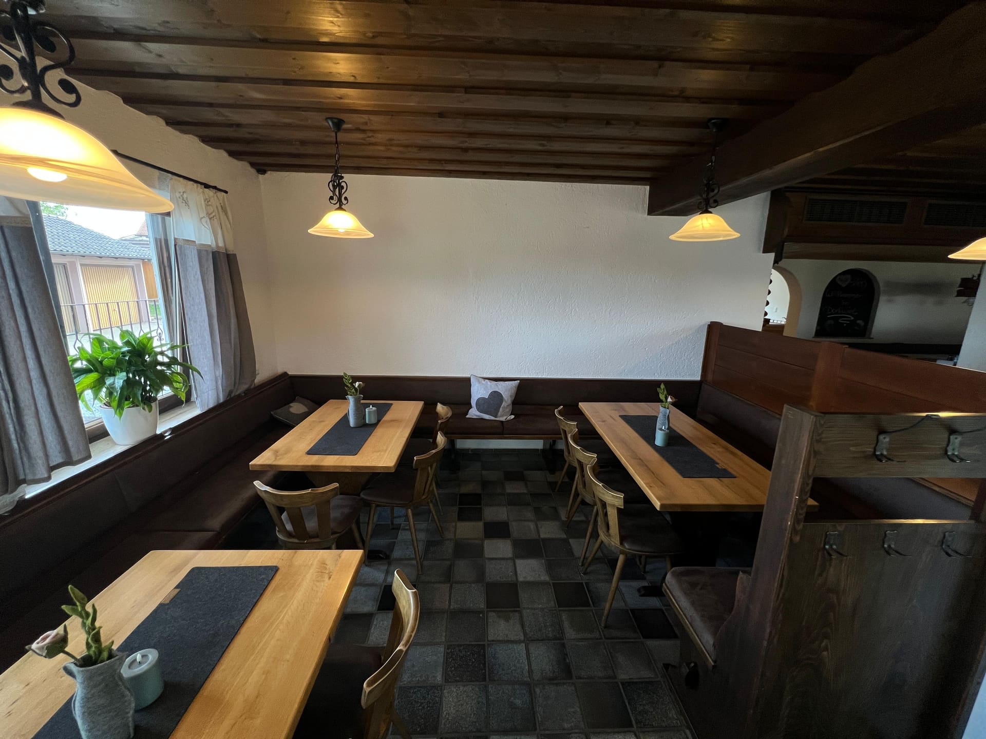 Eckbank und Tische unter der Holzdecke in der Gaststube des Dorfwirts
