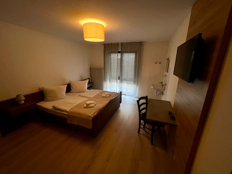 Zimmer 3: Doppelbett, Schreibtisch und Fernseher an der Holzwand