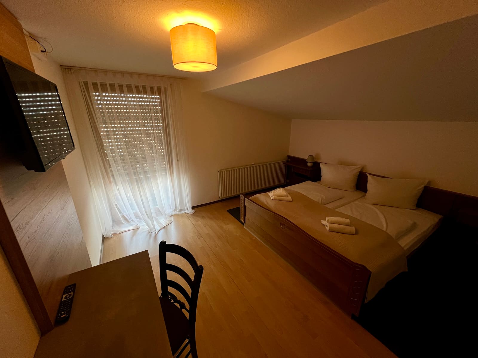 Zimmer 4: Doppelbett unter der Dachschräge, Schreibtisch und Fernseher