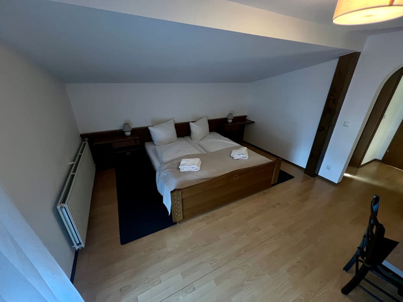 Zimmer 4: Doppelbett mit Holzrahmen, Holzbalken und Rundbogentür