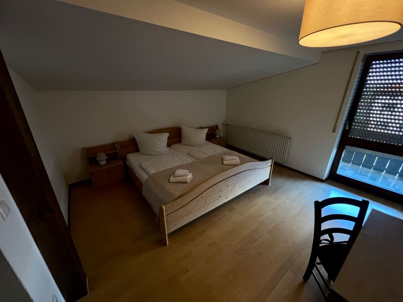 Zimmer 5: helles Holzbett unter der Dachschräge, Balkontür